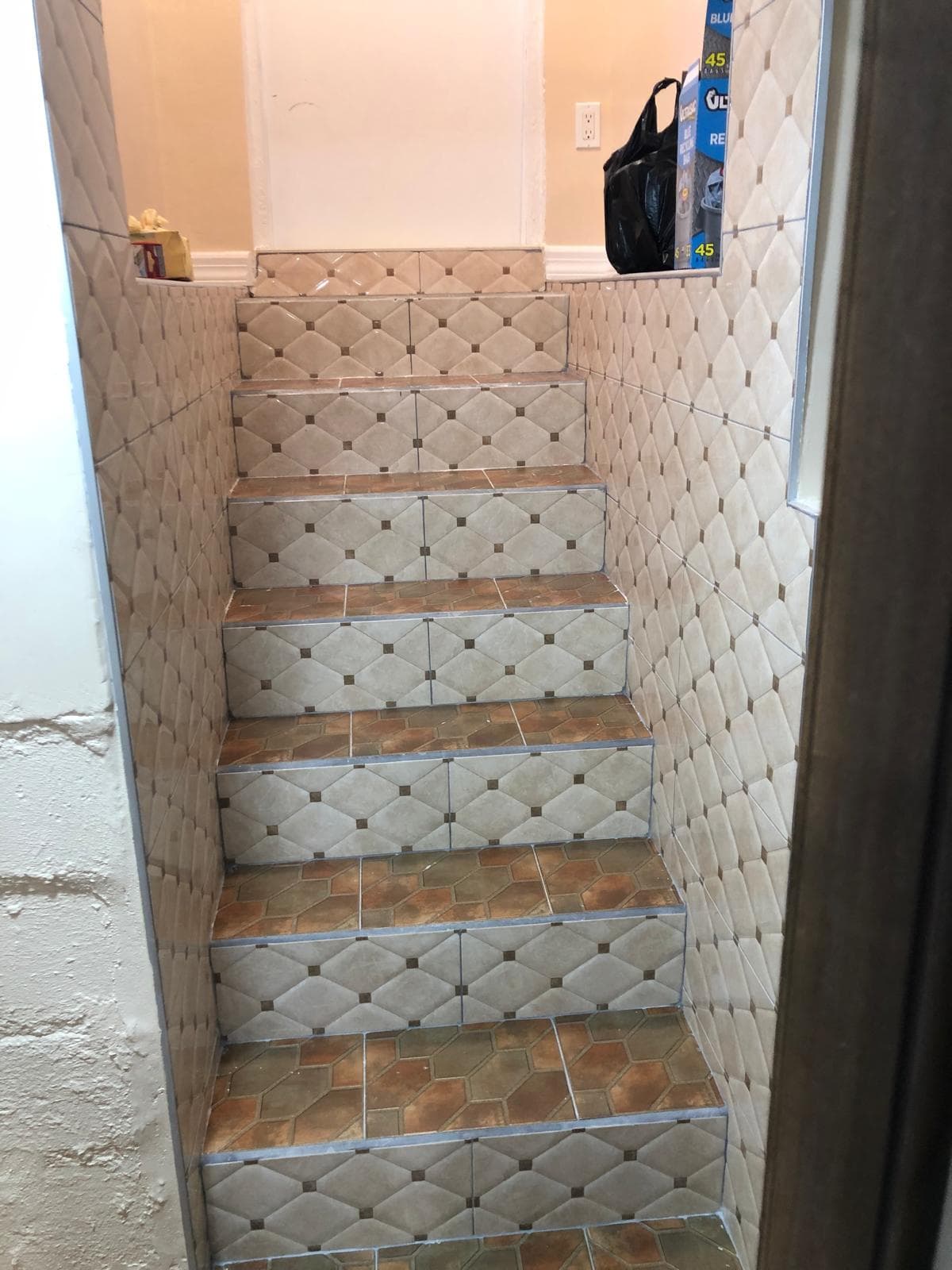 Modern staircase with ceramic tile steps and white risers in a Queens home